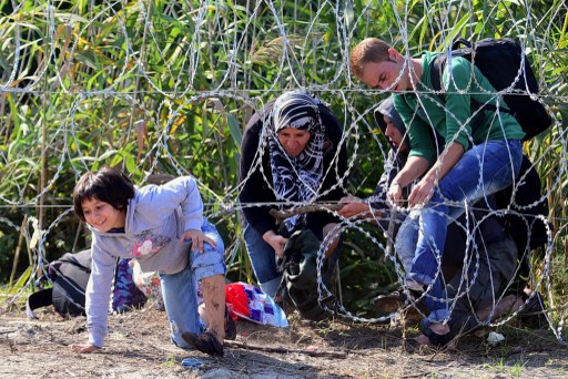 Izbjeglice u pokušaju prelaska opasne bodljikave žice na granici