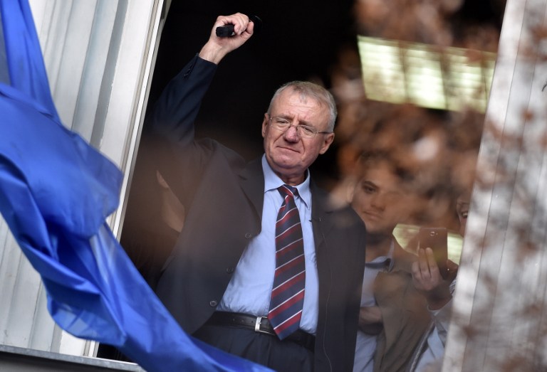 Serb ultranationalist leader Vojislav Seselj waves at supporters on November 12, 2014 after arriving at his Radical Serb Party (SRS) headquarters in Zemun, near Belgrade . Ailing Serb leader Seselj, who has been released from the UN Yugoslav war crimes tribunal, arrived on November 12 from the Netherlands to Serbia. The International Criminal Tribunal for the former Yugoslavia (ICTY) last week ordered Seselj's release so he could return home for cancer treatment as he awaits a verdict on alleged war crimes during the Balkan wars. Seselj, accused of leading ethnic Serb volunteers in persecuting Croats, Muslims and other non-Serbs during the 1990s wars, underwent colon cancer surgery in December. AFP PHOTO / ANDREJ ISAKOVIC