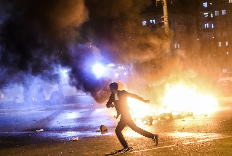 A man runs as smoke billows from burning pallets set on fire during clashes between Turkish riot policemen and Kurdish protesters in the southeastern city of Diyarbakir on November 1, 2015 after first results of the Turkish general election showed a clear victory to the Justice and Development Party (AKP). Turkish police fired tear gas and water cannon at Kurds who were protesting after the election appeared to deliver a clear victory to AKP, an AFP photographer said. Latest results say the pro-Kurdish People's Democratic Party (HDP) won slightly over 10 percent of the vote, just enough to scrape into parliament. AFP PHOTO / BULENT KILIC