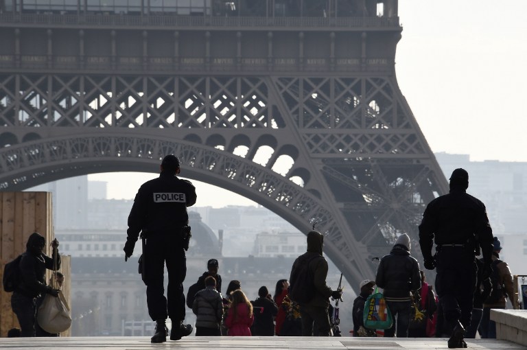French police officers walk near the Eiffel Tower in Paris on December 24, 2015. / AFP / DOMINIQUE FAGET