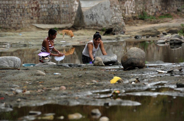 Women wash the dishes at the Guacerique river which flows into the Los Laureles dam reservoir that supplies water for Tegucigalpa, on the outskirts of the capital, on June 2, 2015. Honduras has been hit by a major drought caused by "El Nino" climate phenomenon, a band of unusually warm Pacific ocean temperatures, which in the past has been linked to numerous floods, droughts and bush fires from South America to Australia. The drought has killed thousands of cattle and dried up crops. AFP PHOTO / ORLANDO SIERRA / AFP / ORLANDO SIERRA