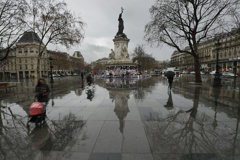People walk on the place de la Republique, on January 7, 2016 in Paris. France hold official ceremonies today marking a year since a jihadist attack on the offices of Charlie Hebdo, with the French satirical magazine defiantly reasserting its provocative spirit. / AFP / ERIC FEFERBERG