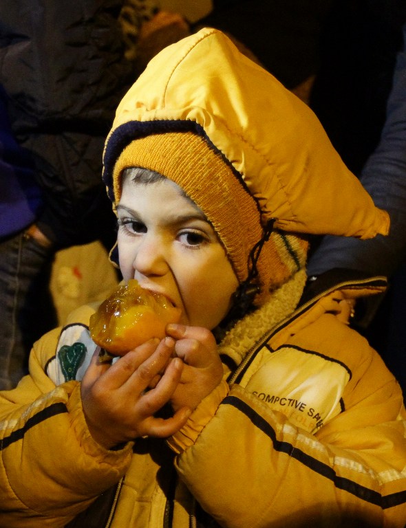 A Syrian child eats a fruit on the outskirts of the besieged rebel-held Syrian town of Madaya, on January 11, 2016, after being evacuated from the town. Dozens of aid trucks headed to Madaya, where more than two dozen people are reported to have starved to death, after an outpouring of international concern and condemnation over the dire conditions in the town, where some 42,000 people are living under a government siege. / AFP / LOUAI BESHARA