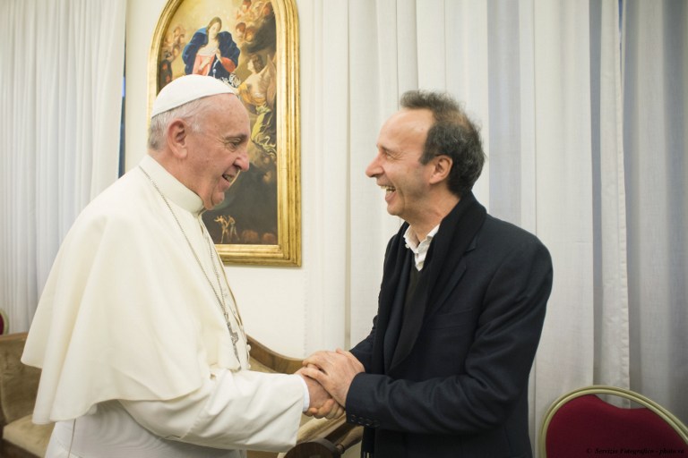 This handout picture released by the Vatican press Office - Osservatore Romano shows Pope Francis (L) welcoming Italian actor and movie director Roberto Benigni (R) as he receives his new book "The name of God is Mercy" (Il nome di Dio è misericordia) at the Vatican, on January 11, 2016. In the book the Pontiff faces the issue of mercy, so central in his teaching and in his personal experience of man, as a priest and pastor. His papacy wanted to personally sign the covers of editions in Italian, English, French, German, Spanish and Portuguese. The book is now available in 86 countries.   / AFP / OSSERVATORE ROMANO / OSSERVATORE ROMANO