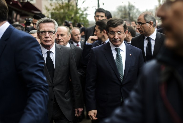 Turkish Prime Minister Ahmet Davutoglu (C) walks with German Interior Minister Thomas De Maiziere (L) on January 13, 2016 in Istanbul, to the site of yesterday's attack in the city's tourist hub of Sultanahmet. Turkish authorities probed how a jihadist from Syria killed 10 mainly German tourists in an attack in the heart of Istanbul that raised alarm over security in the city. / AFP / BULENT KILIC