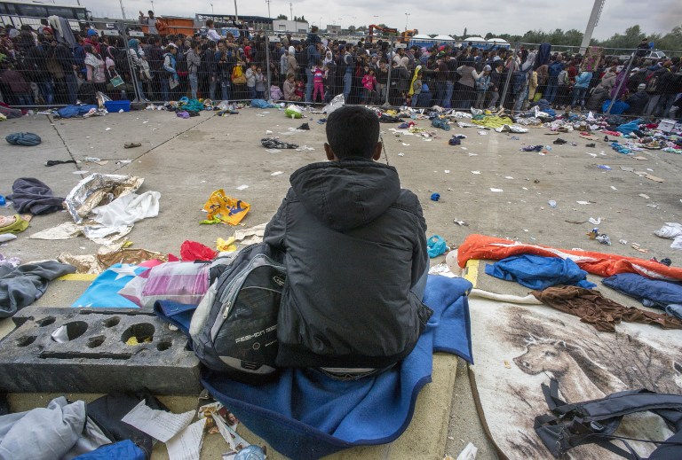 One migrant sits as hundreds are waiting for buses at the former truck custom station near Nickelsdorf, Austria at the border between Hungary and Austria on September 11, 2015. Over eight thousand migrants passed through this location the day before and the same number is expected for today. AFP PHOTO/JOE KLAMAR / AFP / JOE KLAMAR