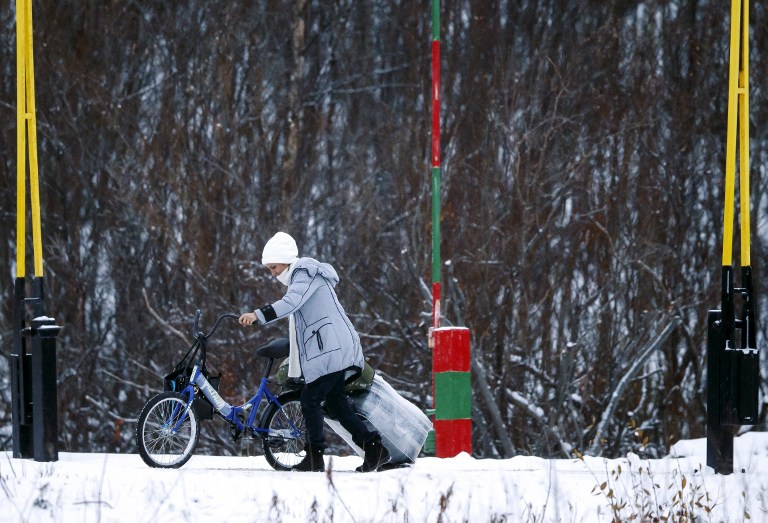 A migrant with a bike and a suitcase crosses the boarder between Norway and Russia in Storskog near Kirkenes in Northern Norway, on November 16, 2015. An increasingly popular route for migrants across Russia and into Norway has Oslo angered and worried as winter approaches, while commentators suspect Moscow is deliberately creating problems for its neighbour. Initially, the news that migrants were making a long detour through the Arctic had a whimsical quality to it: migrants have to make the last section of their journey by bicycle because Russian authorities don't let pedestrians cross the border and Norway considers it human trafficking to transport migrants in a vehicle. AFP PHOTO / NTB SCANPIX / CORNELIUS POPPE +++ NORWAY OUT +++ / AFP / NTB SCANPIX / POPPE, CORNELIUS