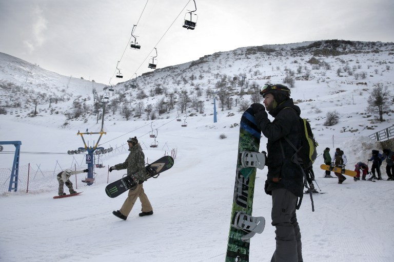 Snowboarders prepare themselves at the Israeli Mount Hermon ski resort, in the Israeli-occupied Golan Heights, on January 21, 2016. For Israelis, the Hermon range, straddling Lebanon and the Syrian and Israeli-held sectors of the Golan, is a highly strategic area under close surveillance. / AFP / THOMAS COEX / TO GO WITH AFP STORY BY DAPHNE ROUSSEAU