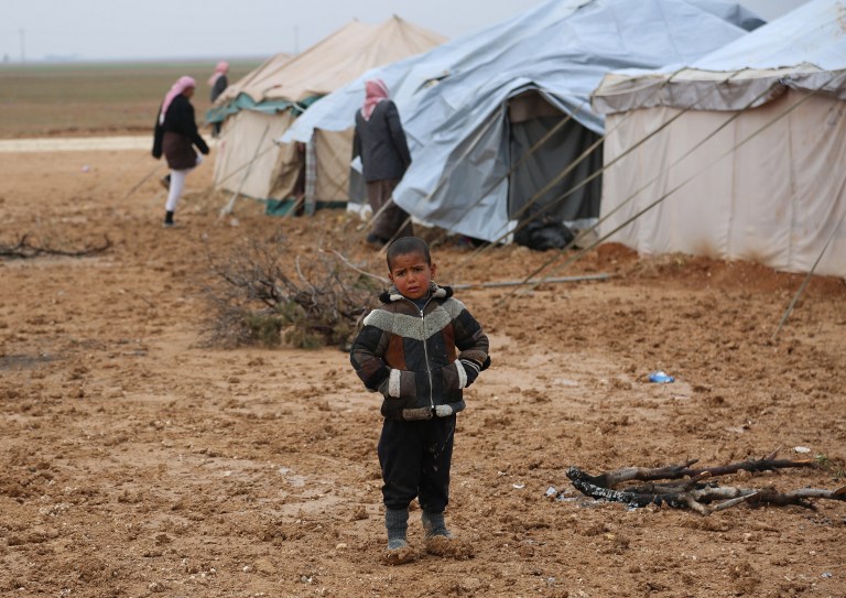 Iraqi refugees, mostly fleeing the northern city of Mosul, now held by the Islamic State (IS) group, stand at a new camp on the outskirts of the Syrian town of Ras al-Ain, near the border with Turkey, on February 2, 2016. The Islamic State group overran large areas north and west of the Iraqi Baghdad in 2014, and Iraqi forces are battling to push the jihadists back. / AFP / DELIL SOULEIMAN