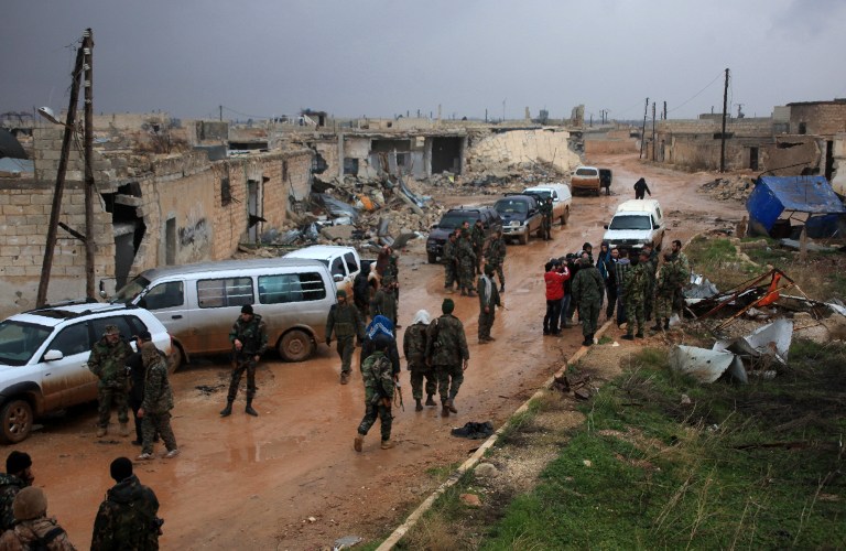 Syrian government soldiers re-group after taking control of the village of Ratian, north of the embattled city of Aleppo, from rebel fighters on February 6, 2016. Thousands of Syrians fled towards Turkey as regime troops pressed a major Russian-backed offensive around Aleppo, that threatens a fresh humanitarian disaster. / AFP / GEORGE OURFALIAN