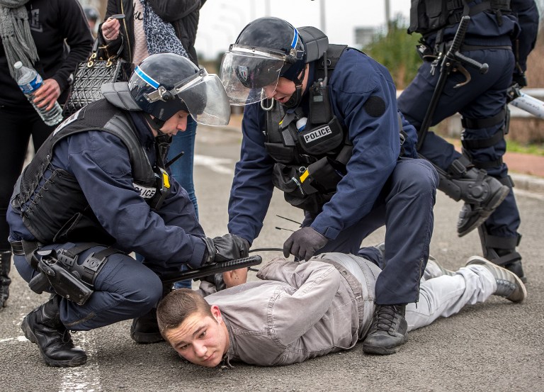 French riot police arrest a supporter of the Pegida movement (Patriotic Europeans Against the Islamisation of the Occident) during a banned demonstration in Calais, northern France, on February 6, 2016. Around 20 anti-migrant protesters were arrested in the French port of Calais after scuffles with police at a banned rally in support of a Europe-wide initiative by the Islamophobic Pegida movement. / AFP / PHILIPPE HUGUEN