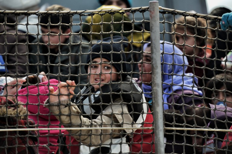Refugees and migrants including children, wait on a ship of the Greek coastguard, at the port of Mytilene, on the Greek island of Lesbos, after crossing the Aegean sea from Turkey, on February 18, 2016. Greece on February 16, 2016 hit back at EU criticism of its handling of the massive migrant influx, saying the time for blaming Athens was "over" as it prepared to open new centres to register refugees. Athens has come under heavy pressure from fellow EU members to control its borders better, with the bloc imposing a three-month ultimatum last week to remedy "deficiencies" or face effective suspension from the Schengen passport-free zone. / AFP / ARIS MESSINIS