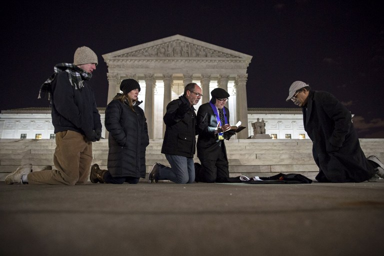 WASHINGTON, DC - FEBRUARY 13: A group of people pray in front of the U.S. Supreme Court February 13, 2016 in Washington, DC. Supreme Court Justice Antonin Scalia was at a Texas Ranch Saturday morning when he died at the age of 79. Drew Angerer/Getty Images/AFP