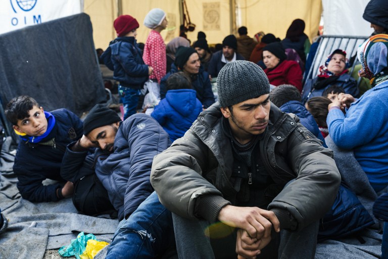 People sit near the gate at the Greek-Macedonian border near the Greek village of Idomeni where thousands of refugees and migrants are stranded on March 8, 2016. European Union leaders on March 7 hailed a "breakthrough" in talks with Turkey on a deal to curb the migrant crisis but delayed a decision until a summit next week to flesh out the details of Ankara's new demands. More than one million refugees and migrants have arrived in Europe since the start of 2015 -- the majority fleeing the war in Syria -- with nearly 4,000 dying while crossing the Mediterranean. / AFP / DIMITAR DILKOFF