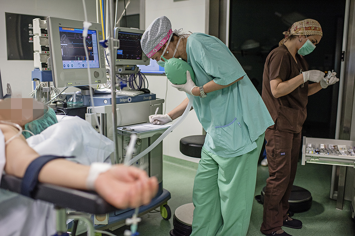 Anesteziologinja radi zapisnik i rednom rukom pridržava respirator