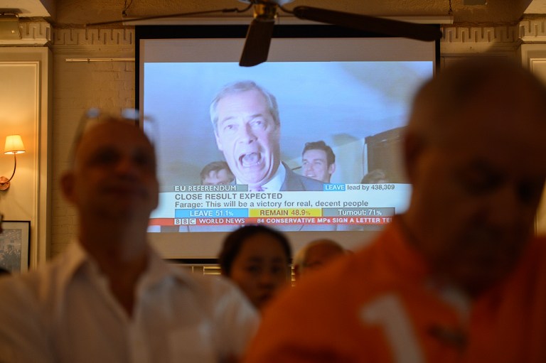 People watch as top anti-EU campaigner Nigel Farage (C, on screen), leader of the UK Indendence Party is seen, during a live broadcast of the Brexit vote, effectively declaring a victory for the Leave campaign, in Hong Kong on June 24, 2016. Britain has voted to break out of the European Union, national media declared on June 24, striking a thunderous blow against the bloc and spreading alarm through markets as sterling plummeted to a 31-year low against the dollar. / AFP PHOTO / ANTHONY WALLACE