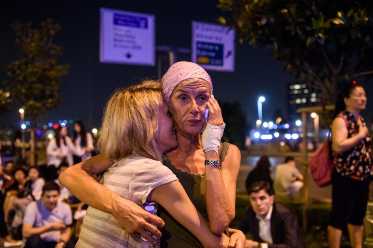 Passengers embrace outside Ataturk airport`s main enterance in Istanbul, on June 28, 2016, after two explosions followed by gunfire hit Turkey's largest airport, killing at least 10 people and injuring 20. All flights at Istanbul's Ataturk international airport were suspended on June 28, 2016 after a suicide attack left at least 36 people dead. / AFP PHOTO / OZAN KOSE