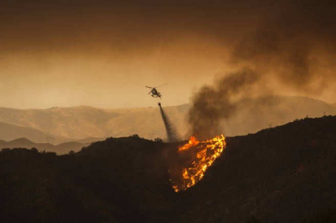 A firefighting helicopter drops water at the Sand Fire on July 23 2016 near Santa Clarita, California. Fueled by temperatures reaching about 108 degrees fahrenheit, the wildfire began yesterday has grown to 11,000 acres. / AFP PHOTO / DAVID MCNEW