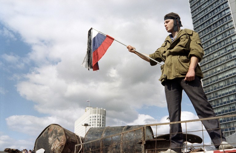 A man waves a russian flag during the funeral procession of victims of the coup in front of the Russian White House in Moscow on August 24, 1991, after the coup attemp failed. / AFP PHOTO / DIMITRI KOROTAYEV