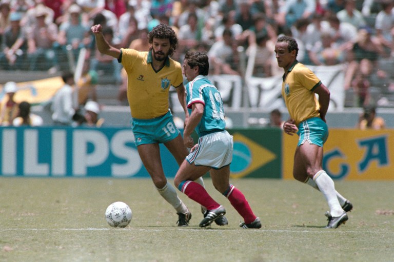 French Alain Giresse (C) vies with Brazilian players Socrates (L) and Elzo (R), on June 21, 1986 in Guadalaraja, during the World Cup quarterfinal soccer match between France and Brazil. / AFP PHOTO / STRINGER
