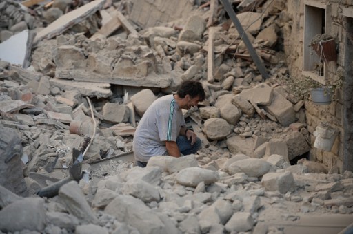 A man reacts to his damaged home after a strong heartquake hit Amatrice on August 24, 2016. Central Italy was struck by a powerful, 6.2-magnitude earthquake in the early hours, which has killed at least three people and devastated dozens of mountain villages. Numerous buildings had collapsed in communities close to the epicenter of the quake near the town of Norcia in the region of Umbria, witnesses told Italian media, with an increase in the death toll highly likely. / AFP PHOTO / FILIPPO MONTEFORTE