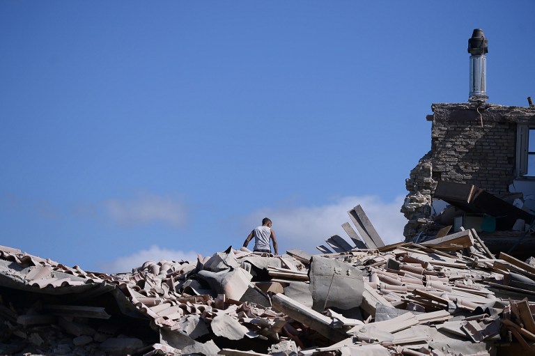 A man sits on top of rubble in Amatrice on August 24, 2016 after a powerful earthquake rocked central Italy. The earthquake left 38 people dead and the total is likely to rise, the country's civil protection unit said in the first official death toll. Scores of buildings were reduced to dusty piles of masonry in communities close to the epicentre of the pre-dawn quake in a remote area straddling the regions of Umbria, Marche and Lazio. / AFP PHOTO / FILIPPO MONTEFORTE