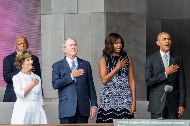 (L-R) Former US First Lady Laura Bush, former US President George W. Bush, First Lady Michelle Obama, and President Barack Obama stand for the The National Anthem during the opening ceremony for the Smithsonian National Museum of African American History and Culture on September 24, 2016 in Washington, D.C. / AFP PHOTO / ZACH GIBSON