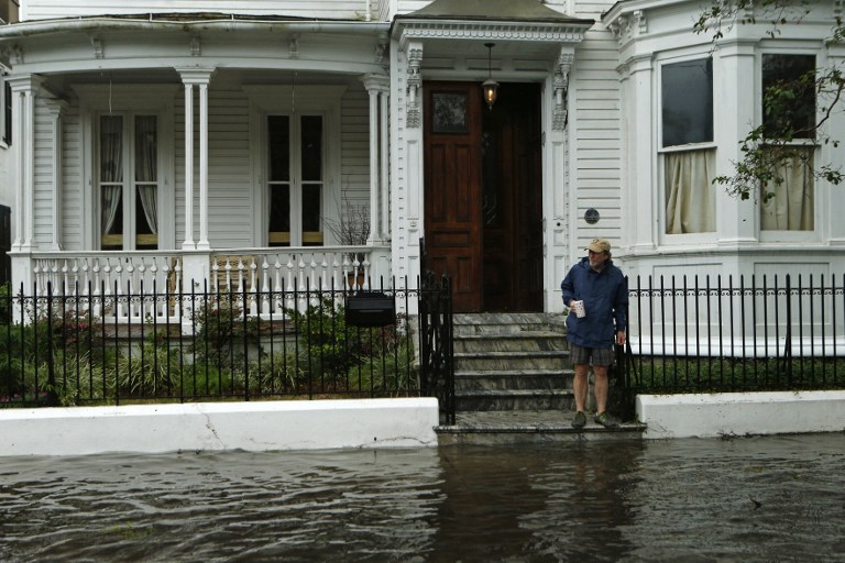 CHARLESTON, SC - OCTOBER 8: A resident stops short of the flooded sidewalk as he makes his way to the edge of the steps in front of a friend's home on Broad St. in the wake of Hurricane Matthew on October 8, 2016 in Charleston, South Carolina. Across the Southeast, Over 1.4 million people have lost power due to Hurricane Matthew which has been downgraded to a category 1 hurricane on Saturday morning. Brian Blanco/Getty Images/AFP