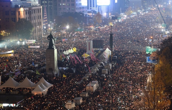 Tens of thousands of protesters hold candles during an anti-government rally in central Seoul on November 19, 2016 aimed at forcing South Korean President Park Geun-Hye to resign over a corruption scandal. The demonstrations -- among the largest seen in South Korea since the pro-democracy protests of the 1980s -- have provided a stark challenge to Park's authority, but the president has defied calls to step down. / AFP PHOTO / POOL / JUNG YEON-JE