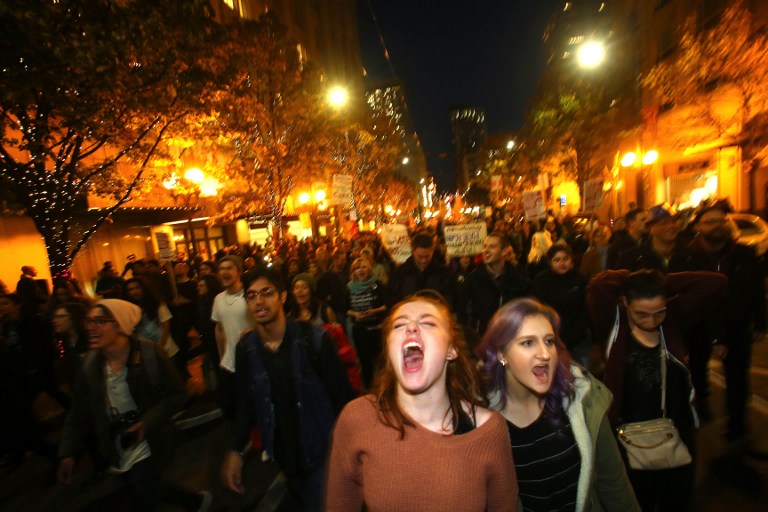 SEATTLE, WA - NOVEMBER 09: Sasha Savenko (C) and Sydney Kane (C, Right), both students at the University of Washington, join thousands of protesters march down 2nd Avenue on November 9, 2016 in Seattle, Washington. Demostrations in multiple cities around the country were held the day following Donald Trump's upset win in last night's U.S. presidential election. Karen Ducey/Getty Images/AFP