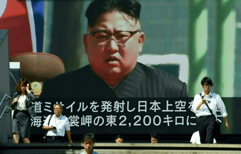 Pedestrians walk in front of a large video screen in Tokyo broadcasting a news report showing North Korean leader Kim Jong-Un, following a North Korean missile test that passed over Japan on September 15, 2017.
North Korea fired a ballistic missile over Japan and into the Pacific on September 15, responding to new UN sanctions with what appeared to be its furthest-ever missile flight amid high tensions over its weapons programmes. / AFP PHOTO / Toru YAMANAKA