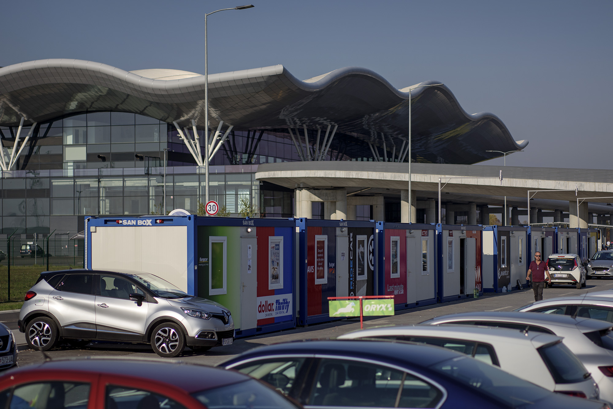 Novi terminal zagrebačkog aerodroma, vrijedan oko 300 milijuna eura, počeo se graditi prije pet godina. Dovršen je i svečano predstavljen u ožujku prošle godine. Ima 65 tisuća kvadrata, na četiri razine. No, godinu i pol nakon pompoznog otvaranja, na parkiralištu aerodroma stoje ovi otužni limeni kontejneri.
