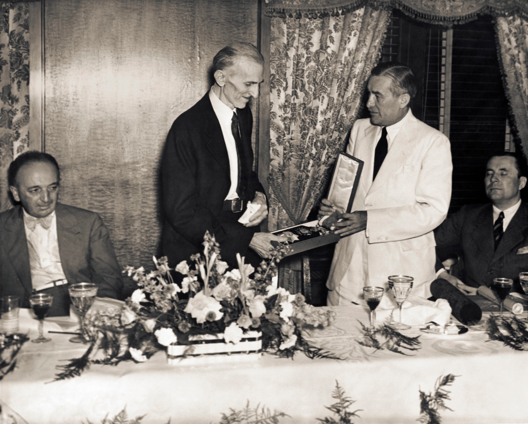 Ovdje je snimljen dan ranije, 10. srpnja 1935., na svečanoj večeri njemu u čast. Čehoslovački izaslanik <b>Vladimir Hurban</b> Tesli dodjeljuje medalju Reda bijelog lava prvog stupnja. Na istoj večeri, izaslanstvo Kraljevine Jugoslavije Tesli je poklonilo medalju Reda bijelog orla prvog stupnja.
