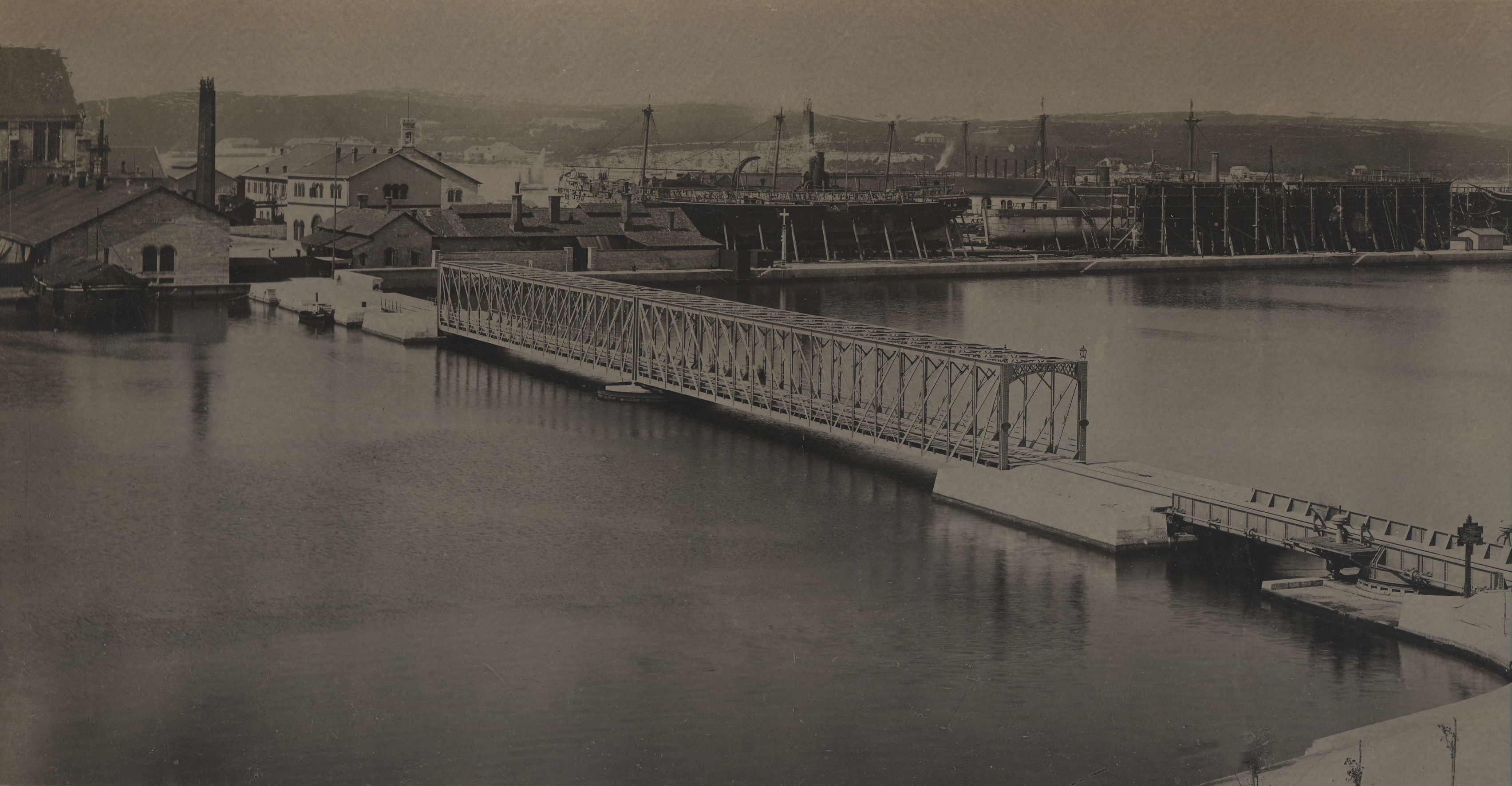Na tom otočiću smješteni su bili tad, kao i danas, objekti i glavni pogoni brodogradilišta, a s obalom je povezan mostom. Na fotografiji je konstrukcija željeznog mosta od Rive prema brodogradilištu na otoku Uljanik, izgrađenog 1882. godine