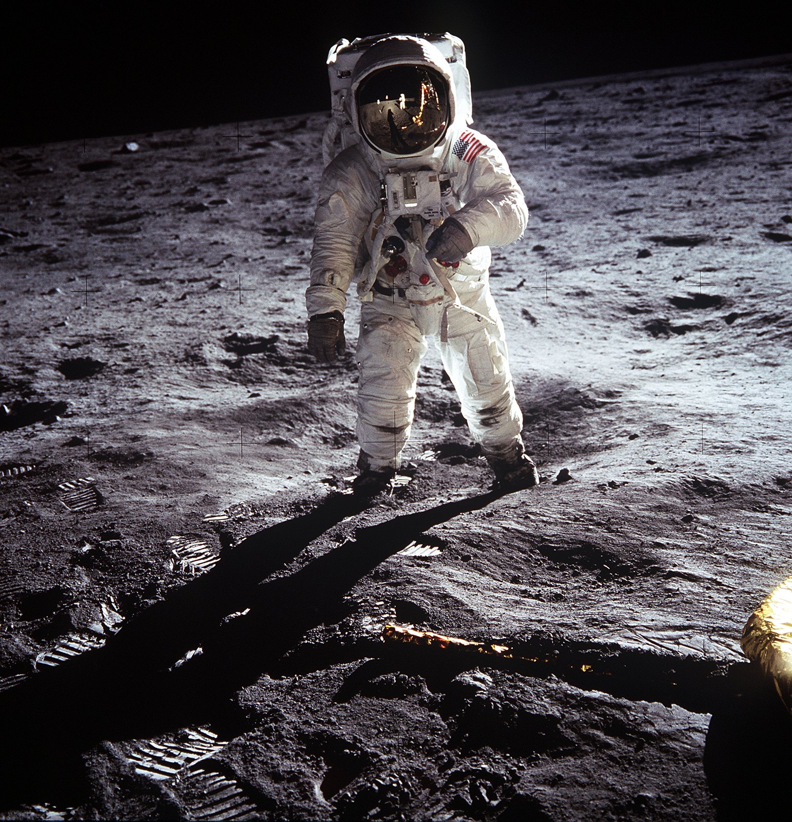 Buzz Aldrin hoda po površini Mjeseca. Fotografija je snimljena nedaleko lunarnog modula, budući da se na fotografiji vidi i jedna noga za slijetanje. Fotografiju Aldrina snimio je Neil Armstrong sa svojom 70mm lunarnom kamerom, dok je Michael Collins ostao unutar komandnog modula.